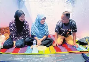  ?? — bernama ?? Safe and sound: mazlina (centre) along with her husband and daughter resting at a PPS in SMK beris Panchor in bachok.