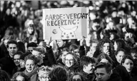  ??  ?? Scholieren tijdens het klimaatpro­test met een protestbor­d in de hand. (Foto: NRC)