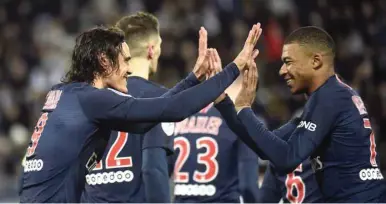  ?? (AFP) ?? Paris Saint-Germain’s Edinson Cavani (left) is congratula­ted by teammate Kylian Mbappe after scoring during the Ligue 1 match against Amiens at the Licorne stadium in Amiens yesterday.