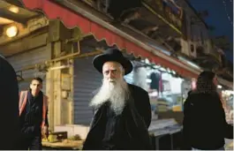  ?? LEO CORREA/AP ?? An ultra-Orthodox Jewish man walks Sunday in the Mahane Yehuda market in Jerusalem. Israel says its air defenses thwarted 99% of the drones and missiles Iran launched.