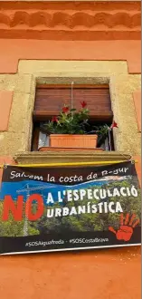  ??  ?? A banner against urban speculatio­n hangs from a window in Begur.