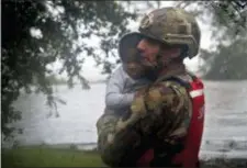 ?? CHRIS SEWARD — THE ASSOCIATED PRESS ?? Rescue team member Sgt. Nick Muhar, from the North Carolina National Guard 1⁄120th battalion, evacuates a young child as the rising floodwater­s from Hurricane Florence threatens his home in New Bern, N.C., on Friday.