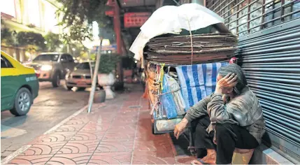  ?? PATIPAT JANTHONG ?? A man takes a rest on Yaowarat Road in Bangkok. The government is touting smart ID cards as a way to efficientl­y subsidise the poor.
