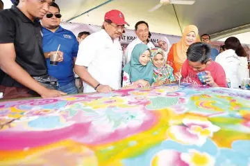  ??  ?? Musa and wife, Datin Seri Panglima Datuk Hajah Faridah Tussin admiring the work of a batik student during their visit to the Sabah Handicraft Centre booth at the launching of the Sabah Foundation Roadshow in Libaran Multi Purpose Hall on Sunday.