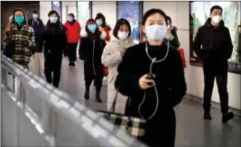  ??  ?? People wearing face masks walk through a subway station in Beijing, on Friday