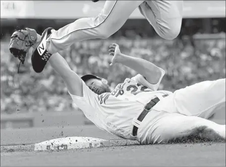  ?? Jayne Kamin-Oncea Getty Images ?? DODGERS PITCHER Clayton Kershaw slides into first base and tags out Pittsburgh Pirates outfielder Bryan Reynolds in the second inning, upending the runner in the process. Kershaw gave up four hits and one run in seven innings, and struck out eight batters.