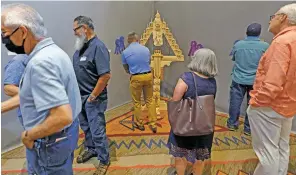  ?? ?? ABOVE: People admire the best-inshow piece by artist Carlos Santisteva­n Sr. during the Traditiona­l Spanish Market preview Friday at the Santa Fe Community Convention Center. The sculpture was carved from pine and aspen and took roughly six to nine months to complete.