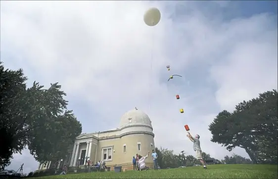  ?? Steve Mellon/Post-Gazette ?? Russell Clark of the University of Pittsburgh releases a high-altitude balloon Friday at Allegheny Observator­y for a test flight in preparatio­n for the total eclipse of the sun Aug. 21. The team launched cameras, computers, light sensors and other...