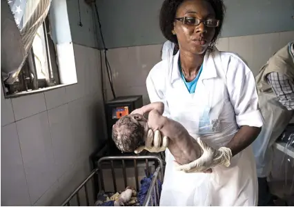  ??  ?? La matrona Gloria Gabor, de 32 años, a punto de lavar y pesar al primer hijo de Fanna Bulama, de 15 años. El bebé nació en una de las clínicas de Nigeria en las que, con ayuda de UNICEF, operan las 'Matronas voladoras'.