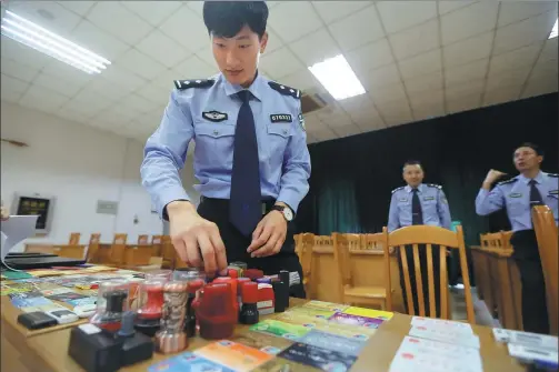  ?? SHE YOU / FOR CHINA DAILY ?? A police officer checks bank cards and plastic stamps confiscate­d during a crackdown on undergroun­d banks in Shenzhen, Guangdong province, in November.