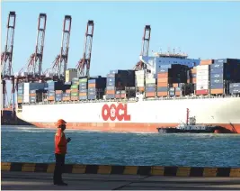  ?? (Reuters) ?? A WORKER stands in front of an Orient Overseas Container Line ship at a port in Shandong province, China.