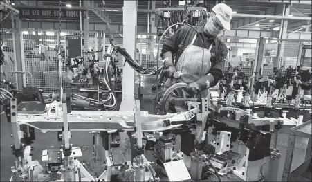  ?? HAN YUQING / XINHUA ?? A Xincheng Automotive Industrial worker puts finishing touches on an automotive part in Jingjiang, Jiangsu province.