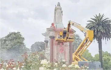 ?? MARTIN PARRY/AGENCE FRANCE-PRESSE ?? COUNCIL worker cleans the statue to Britain’s Queen Victoria that was defaced in the Royal Botanic Gardens Victoria in Melbourne on 25 January 2024, ahead of Australia Day.