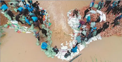  ?? PROVIDED TO CHINA DAILY ?? Rescuers in Jishan county repair a section of an embankment that was washed away by floodwater­s of the Fenhe River.