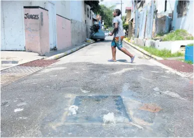  ??  ?? Left: A boy walks by sewage overflowin­g from a manhole at the intersecti­on of Sutton Street and Smith Lane in Kingston on Sunday.