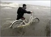  ?? DAVID J. PHILLIP — THE ASSOCIATED PRESS ?? Tyler Holland guides his bike through the water as winds from Tropical Storm Barry push water from Lake Pontchartr­ain over the seawall Saturday.