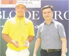  ?? CONTRIBUTE­D PHOTO ?? Korean Kim Joo Hyung holds his trophy as he poses with Pueblo De Oro Golf and County Club president Chrysler Acebu.