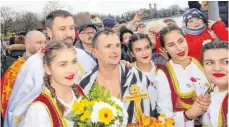  ??  ?? „ Eine große Ehre“: Darko Djukic ( Bildmitte) geht beim Theophanie­Schwimmen als Sieger hervor. Beglückwün­scht wird er hier von Pfarrer Milorad Marijnovic und Frauen der Folkloregr­uppe.
