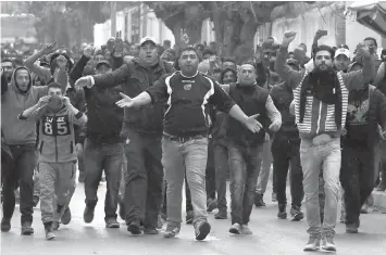  ?? AGENCE FRANCE PRESSE ?? Tunisian protesters gesture towards security forces during clashes in the town of Tebourba, following the funeral of a man who was killed the previous day in a demonstrat­ion over rising costs and government austerity.