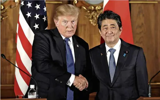  ?? Kiyoshi Ota/AFP ?? Donald Trump cumpriment­a Shinzo Abe, após entrevista em Tóquio; o premiê japonês disse que seu país pode vir a derrubar mísseis norte-coreanos