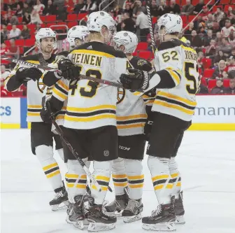  ?? AP PHOTO ?? GROUP HUG: Danton Heinen and the B’s celebrate his goal during last night’s victory against the Red Wings in Detroit.