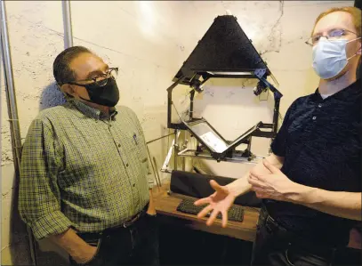  ?? PHOTOS BY JOEL ROSENBAUM — THE REPORTER ?? Brian Irwin (right) of the Vacaville Historical Council discusses the new large-book scanner that the organizati­on recently purchased with a grant from Solano County Supervisor, John Vasquez (left) Tuesday at the organizati­on’s office in downtown Vacaville. The device will allow volunteers to better archive historical items from yearbooks to newspapers and old festival programs.