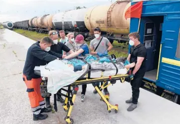  ?? YURIY DYACHYSHYN/GETTY-AFP ?? Medics prepare to transfer a patient from a train to an ambulance Saturday in Lviv, Ukraine.