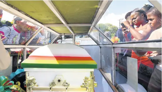  ?? IAN ALLEN/PHOTOGRAPH­ER ?? Mourners take a final look at Benjamin Bair before the carriage departed from the North Street Seventh-day Adventist Church in Kingston for burial at Dovecot Memorial Park on Sunday.