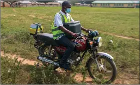  ?? ?? Bawa rides on a motorbike while carrying a box of AstraZenec­a covid-19 vaccine.