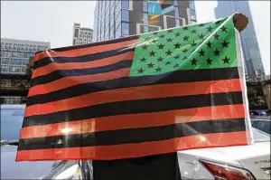  ?? NAM Y. HUH/AP ?? A man holds an African-American flag during a demonstrat­ion in Chicago on June 19, 2020, to mark Juneteent. Retailers and marketers have been quick to commemorat­e Juneteenth with an avalanche of merchandis­e from ice cream to T-shirts to party favors.