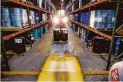  ??  ?? Jose Flores drives chemicals through the warehouse at Palmer Logistics, a distributi­on company.