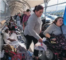 ?? PAUL RATJE / AFP / GETTY IMAGES ?? Pedestrian­s in El Paso, Texas, make their way through an encampment of migrants occupying a bridge.