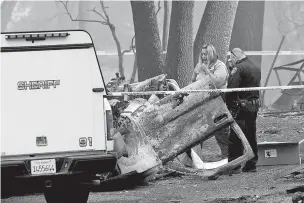  ?? NOAH BERGER/ASSOCIATED PRESS ?? A sheriff’s deputy recovers the remains of a Camp Fire victim from an overturned car in Paradise, Calif., on Thursday.