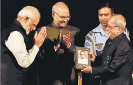  ?? PTI ?? Prime Minister Narendra Modi presents a copy of a book to President Pranab Mukherjee as President elect Ram Nath Kovind looks on at Rashtrapat­i Bhavan in New Delhi on Monday.