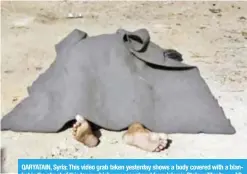  ??  ?? QARYATAIN, Syria: This video grab taken yesterday shows a body covered with a blanket in the street of this town which was recaptured from Islamic State militants. —AP