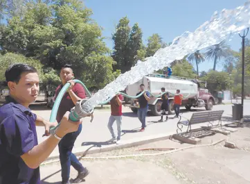  ??  ?? • Los estudiante­s próximos a egresar de la preparator­ia riegan con pipas el Parque Madero, uno de los principale­s "pulmones" de Hermosillo.