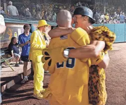  ?? NATHAN DOMINITZ/SAVANNAH MORNING NEWS ?? Savannah Bananas Premier Team head coach Eric Byrnes, right, hugs player Jonny Gomes after he scored the winning run in the final inning of a victory over the Party Animals on Aug. 20 at Grayson Stadium. Byrnes and Gomes are former Major League Baseball players who have participat­ed in Banana Ball games.