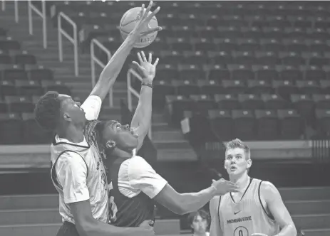  ?? MATTHEW DAE SMITH/LANSING STATE JOURNAL ?? MSU freshman Xavier Booker, left, looks to block the shot of fellow freshman Coen Carr during practice at the Breslin Center in East Lansing on Oct. 3. Also pictured is sophomore Jaxon Kohler.