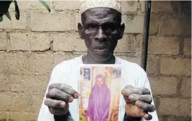  ?? AMINU ABUBAKAR/AFP/GETTY IMAGES ?? Sani Garba, 55, holds the picture of his 14-year-old daughter-in-law Wasila Tasi’u. A Nigerian court has dropped murder charges against her.