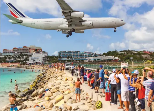  ??  ?? On a wing and a prayer: Planespott­ers come from all over the world to see jets like this coming in to land over Maho Beach