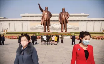  ?? — AFP photo ?? People wearing face masks leave after laying flowers before the statues of Il Sung and Jong Il on the occasion of the 108th birthday of Il Sung in Pyongyang.