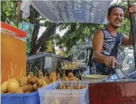  ?? ROMAN PROSPERO ?? His own boss! An ambulant vendor is all smiles as he tends to his business of selling “kwek-kwek” or marinated quail eggs and other favorite street foods in Manila.