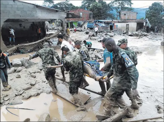  ?? Colombian Army photo via The Associated Press ?? Colombian soldiers carry a victim of river flooding Saturday in the city of Mocoa. At least 193 people were killed, authoritie­s said.