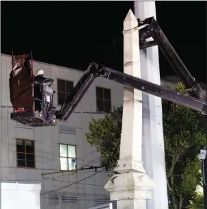  ?? The Associated Press ?? NEW ORLEANS: Workers dismantle the Liberty Place monument, which commemorat­es whites who tried to topple a biracial post-Civil War government, Monday in New Orleans. It was removed overnight in an attempt to avoid disruption from supporters who want...