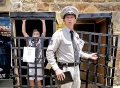  ??  ?? Anthony Woods impersonat­es the character Barney Fife while Nathaniel Bain is locked in a fake jail.