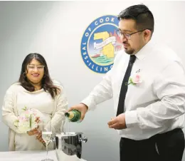  ?? EILEEN T. MESLAR/CHICAGO TRIBUNE ?? Alfonzo Arroyo pours sparkling grape juice for his new wife, Angelica Rodriguez, after they got married at the Cook County clerk’s office on Tuesday.