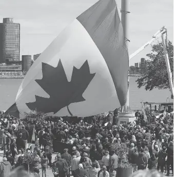  ?? NICK BRANCACCIO ?? The Great Canadian Flag gathers air for the first time during the official flag raising in front of a large crowd at the foot of Ouellette Avenue on May 20.