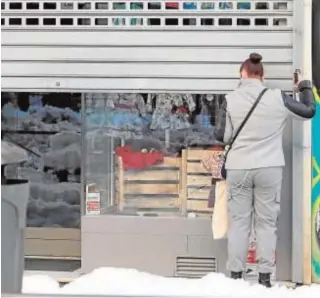  ?? EFE ?? Una empleada limpia de nieve la entrada de su tienda en Madrid