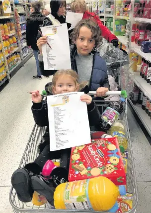  ??  ?? Right, Joseph and Darcey with their list for items as they shop. Now they are urging others to put together Advent food boxes