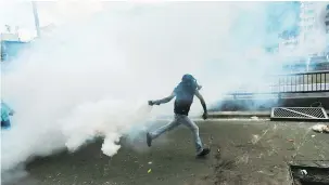  ?? — THE ASSOCIATED PRESS ?? A demonstrat­or throws back a tear-gas canister launched by the police during a protest against Venezuelan President Nicolas Maduro in Caracas on Saturday.